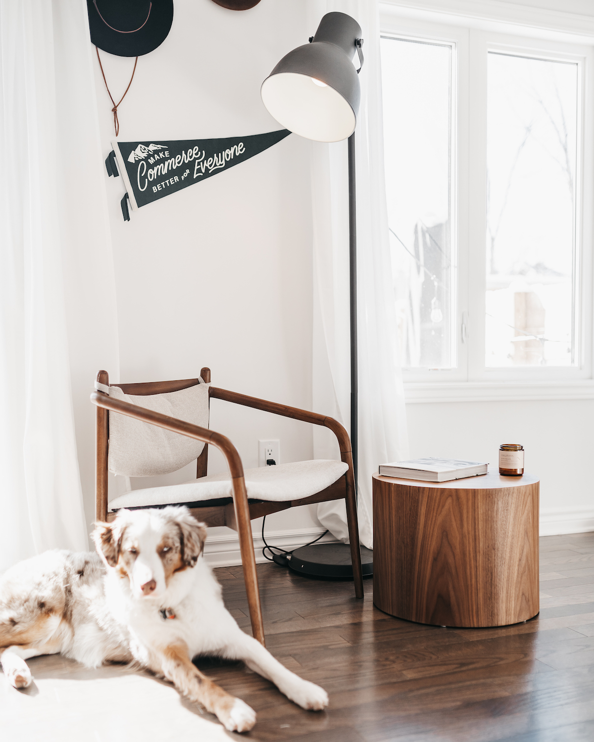 A chair and side table sit side by side in front of a white wall with a flag that says 'Make Commerce Better For Everyone'