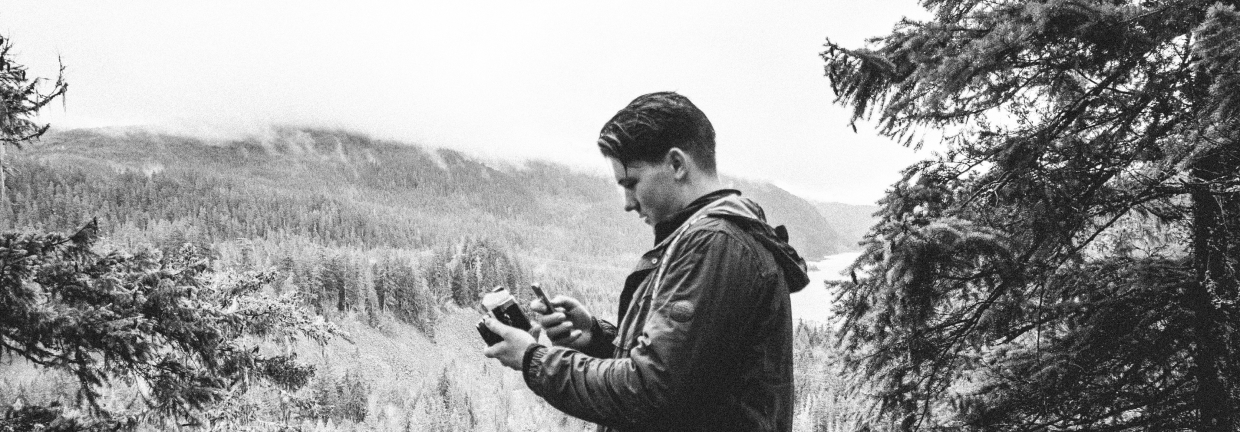 Connell looking at a camera in front of a mountain valley view.